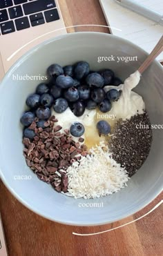 a bowl filled with blueberries, yogurt and other ingredients next to a laptop