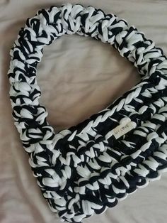 a black and white braided scarf laying on top of a bed