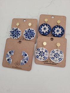 four pairs of blue and white ceramic earrings are displayed on a card with tags attached to them