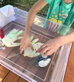 a young boy is making handprints out of paper on a tray with glue