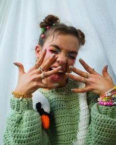 a woman with her hands on her face and fingers in front of her face, wearing rings