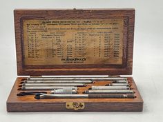 an old wooden box with several different types of tools in it, including pens and pencils