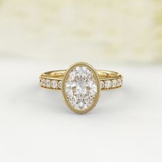 a yellow gold ring with an oval cut diamond in the center and side stones on each band