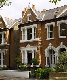 a row of brick houses with white trim and windows on the front, along side a fence