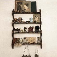 a shelf that has some pictures on it and other items hanging from the wall behind it