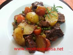 a white plate topped with meat, potatoes and peas on top of a wooden table