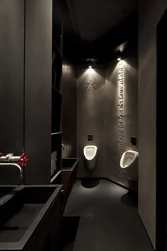 a bathroom with two urinals and lights on the wall