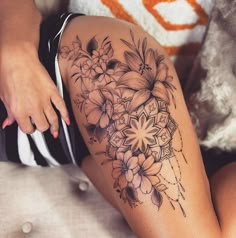 a woman's thigh with flowers on it and an intricate design in the middle