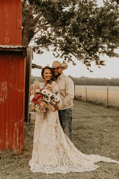 a bride and groom standing in front of a red barn