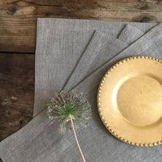 a yellow plate sitting on top of a gray napkin next to a small green plant