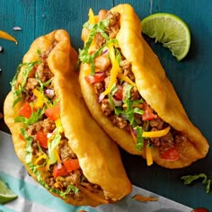 two tacos filled with meat and veggies sitting on top of a table