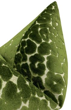 a green and white animal print pillow on top of a bed cover with an open zipper