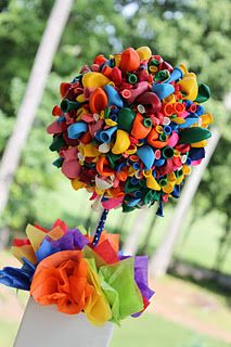 a colorful flower arrangement in a white vase on a table with trees in the background