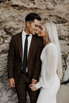 a man in a suit and tie standing next to a woman wearing a white dress