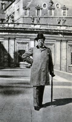 an old black and white photo of a man holding a cane in front of a building