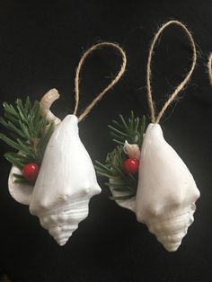 three ornaments are hanging from twine with red berries