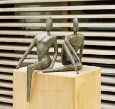 two statues sitting on top of a wooden block