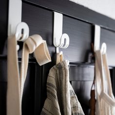 towels hanging from hooks on the wall in front of a black cabinet with white handles