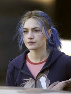 a woman with blue hair is looking at the camera