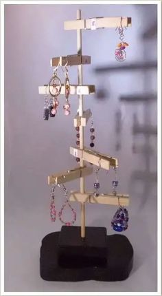 a small wooden tree with earrings hanging from it's sides on a black stand