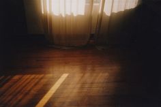 the sun shines through the curtains in an empty room with wood floors and wooden flooring