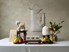 a table topped with figurines and fruit on top of a white table cloth