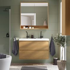 a bathroom with green walls and white fixtures, including a wooden sink cabinet and mirror