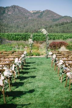 an outdoor ceremony set up with wooden chairs and flowers