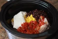 a crock pot filled with beans, corn and other food items on top of a table