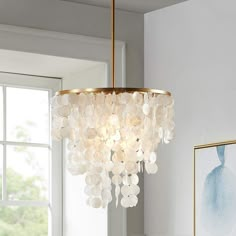 a chandelier hanging from the ceiling in a room with white walls and windows