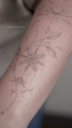 a person with a tattoo on their arm that has flowers and leaves drawn on it