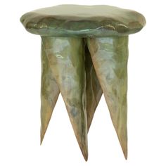 a green stool with two legs that are shaped to look like cones and have long tails