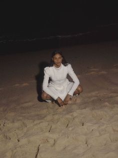 a woman sitting in the sand at the beach