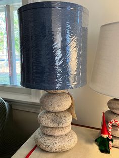 a lamp that is sitting on top of a table next to a stack of rocks