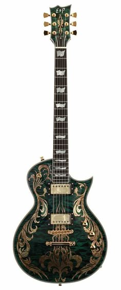 a green and gold guitar sitting on top of a white surface with an intricate design