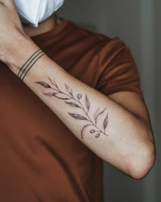 a person wearing a face mask and holding their arm with a flower tattoo on it