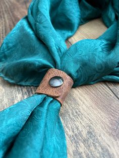 a blue scarf with a wooden button on it sitting on top of a wood table