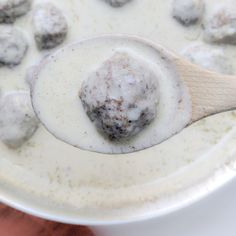 a wooden spoon full of meatballs and gravy in a white saucer