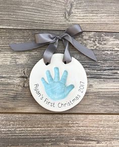 a ceramic ornament with a handprint on it that says baby's first christmas