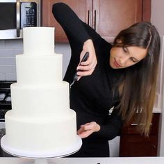 a woman is cutting into a large white cake