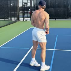 a shirtless man standing on a tennis court