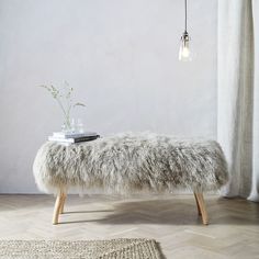 a white bench sitting on top of a hard wood floor next to a window with curtains