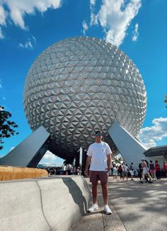 a man standing in front of a large ball at the epcoti disney world