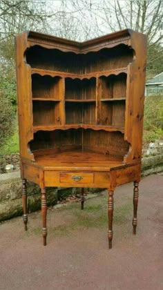 an old wooden desk with shelves and drawers on the top, in front of some trees