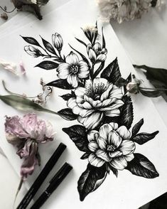 some flowers are sitting on top of a piece of paper next to markers and pens