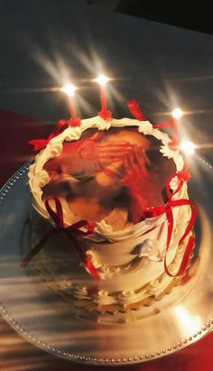 a cake with candles on it sitting on a silver plate in front of a red table cloth