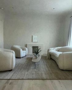 a living room filled with white furniture next to a fire place in a wall mounted fireplace