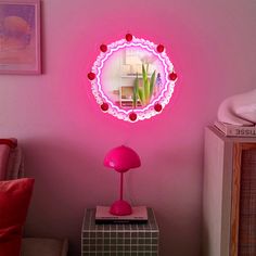 a pink wall with a round mirror on it and a lamp in the corner next to it