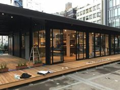 a building with lots of glass doors and windows on top of wooden floors in front of tall buildings