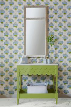 a bathroom with a green vanity and blue wallpaper on the walls next to a mirror